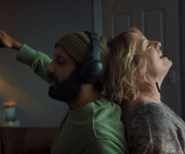 Two people back to back with headphones